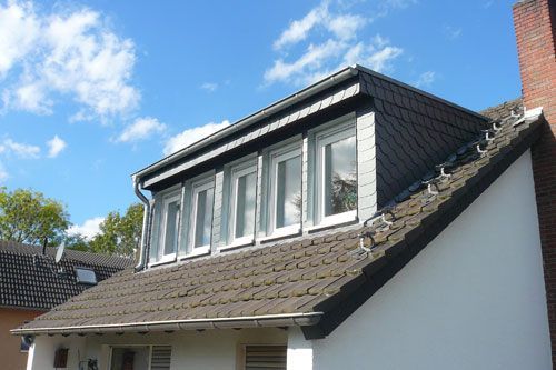 Das Dach eines Hauses hat eine Reihe von Fenstern