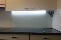 Eine Küche mit Herd, Backofen, Schränken, Schubladen und Licht.