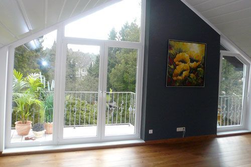 Ein großes Zimmer mit Balkon und einem Gemälde an der Wand.