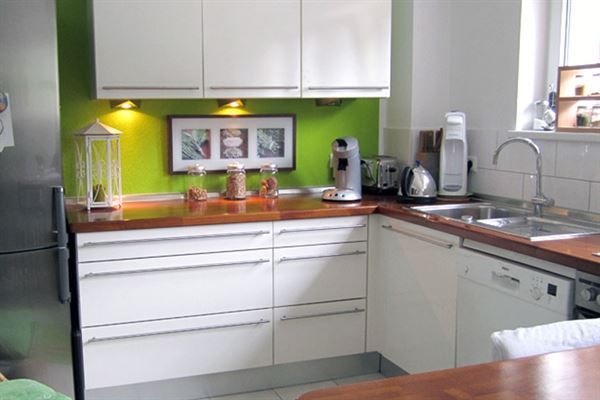 Eine Küche mit weißen Schränken und einer grünen Wand