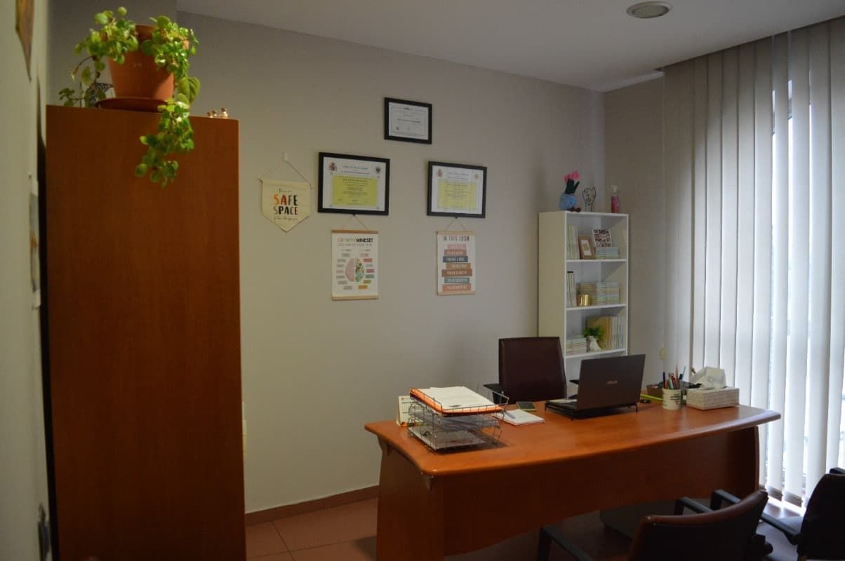 Una oficina con un escritorio y sillas y una computadora portátil encima.