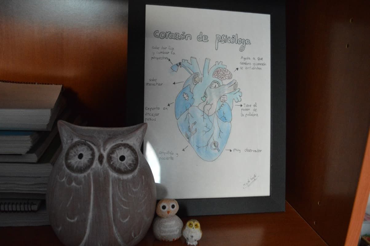 Una estatua de búho está sentada en un estante junto a una imagen enmarcada de un corazón.