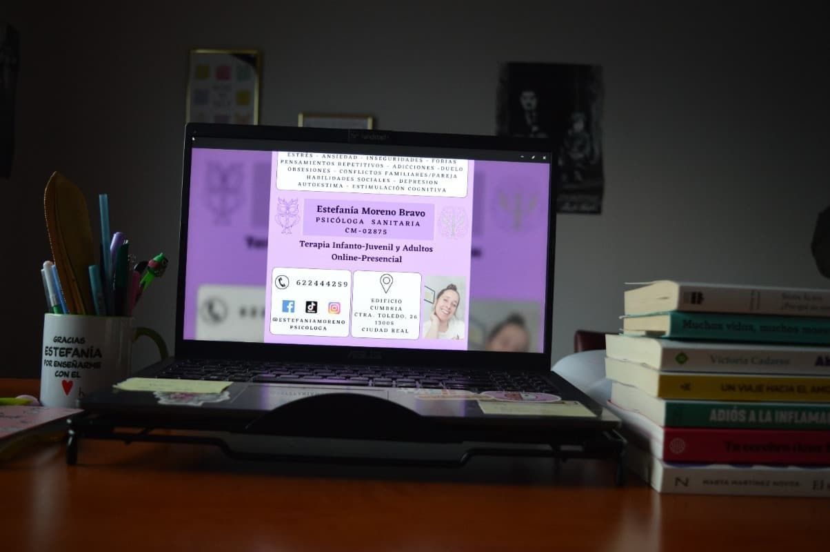 Una computadora portátil está sobre un escritorio al lado de una pila de libros.