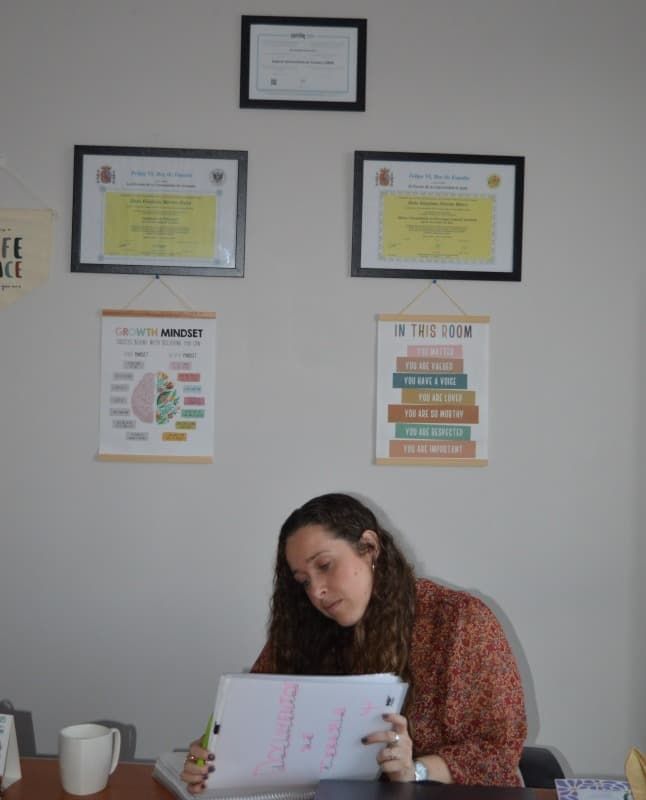 Una mujer está sentada en un escritorio mirando un trozo de papel.