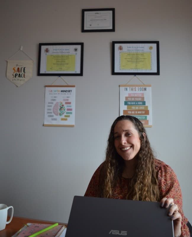 Una mujer está sentada en un escritorio sosteniendo una computadora portátil Asus.