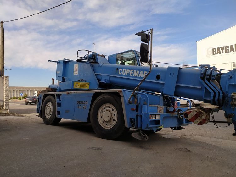 Una grúa azul está estacionada frente a un edificio.