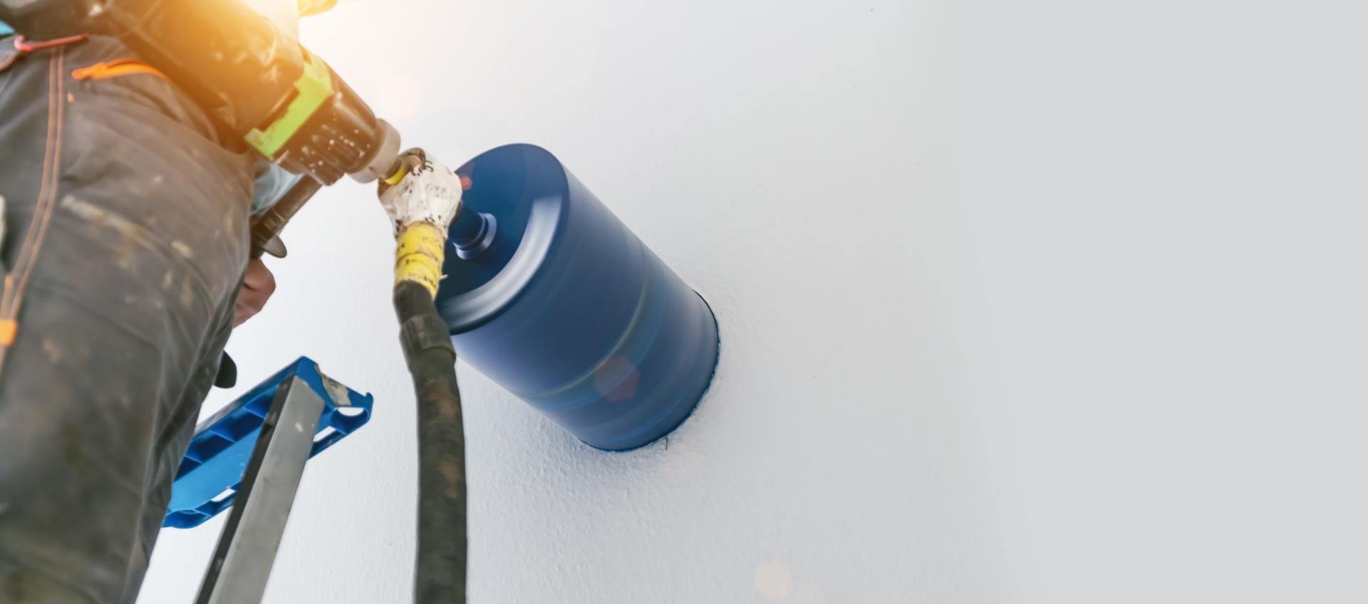 Ein Mann bohrt mit einer Bohrmaschine ein Loch in eine Wand.