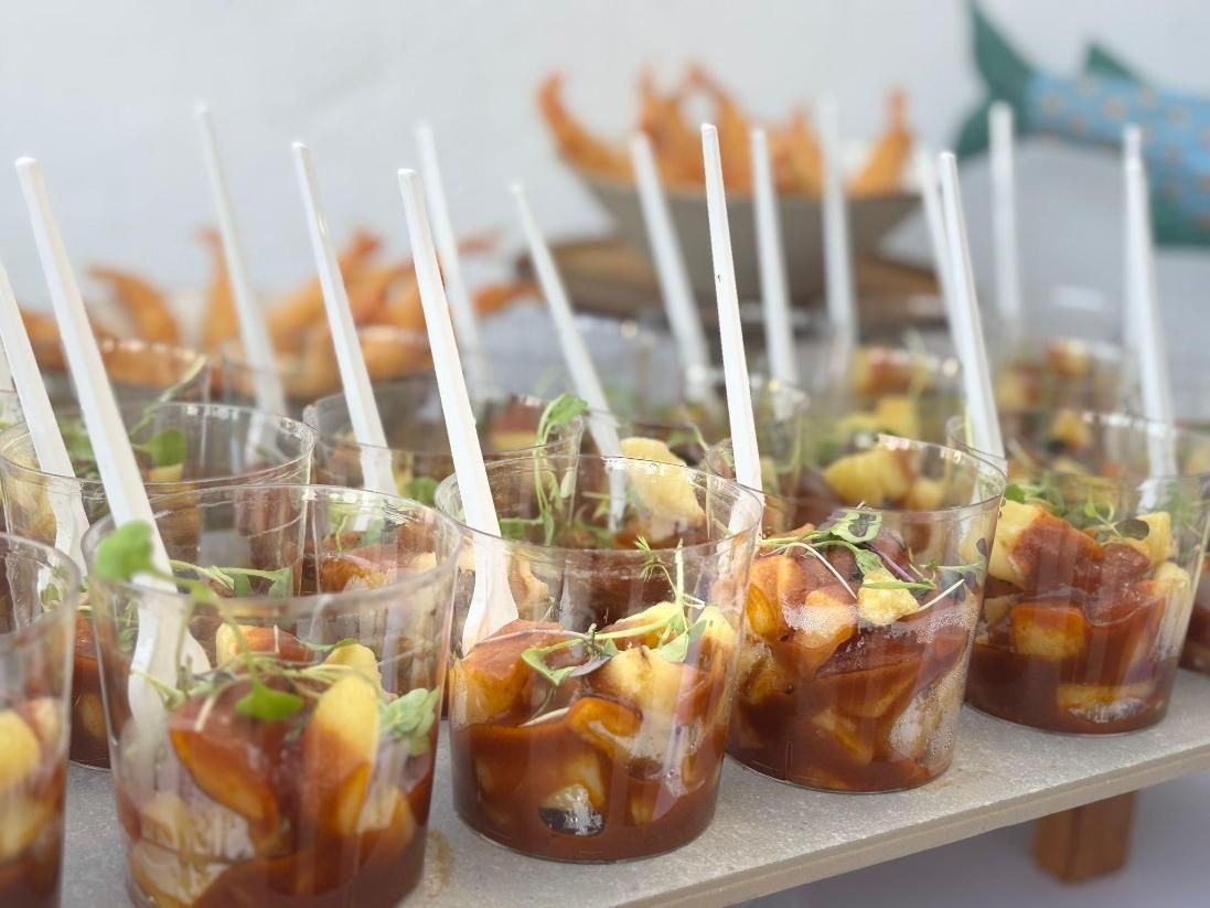 Exhibición de postres en una mesa por la noche con luces de la ciudad de fondo; cajas de madera y varios postres.