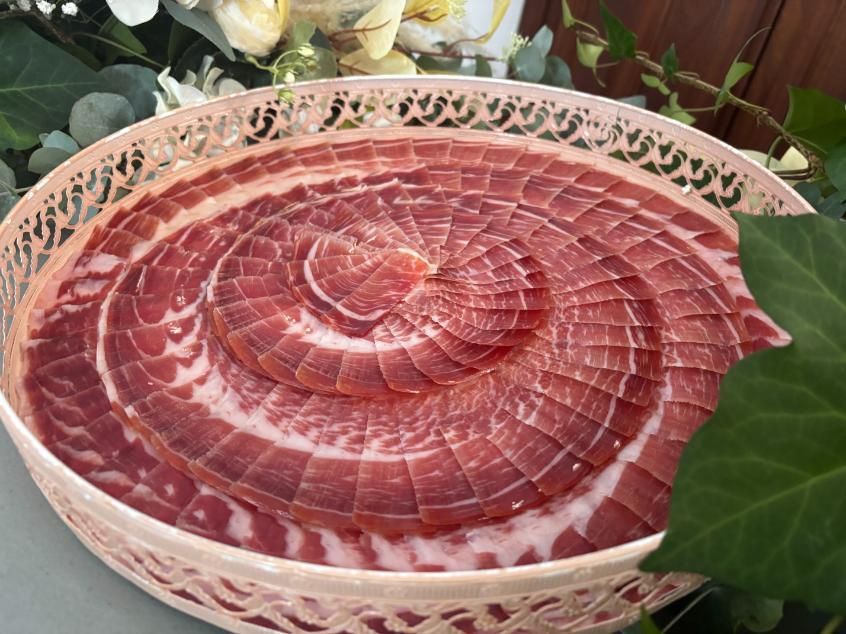 Carne curada cortada en lonchas finas, mayoritariamente roja con vetas blancas.