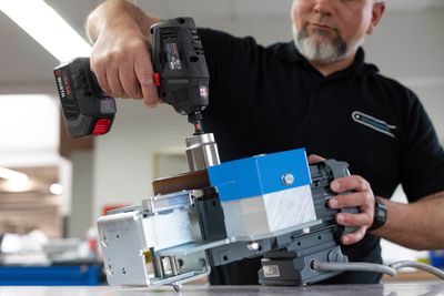 Ein Mann arbeitet mit einer Bohrmaschine an einer Maschine.