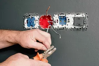Una persona está trabajando en un tomacorriente en una pared.