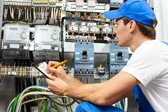 Un electricista está arrodillado y escribiendo en un portapapeles.