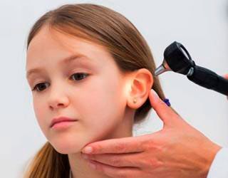 A una niña le examina el oído un médico.