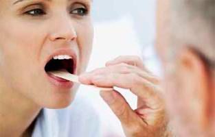 A una mujer le examina la garganta un médico.