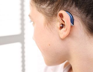 Una mujer lleva un audífono en su oído izquierdo.