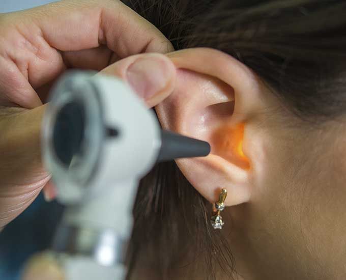 Una mujer se hace examinar los oídos por un médico.