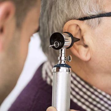 Un hombre sostiene un estetoscopio en su oído.