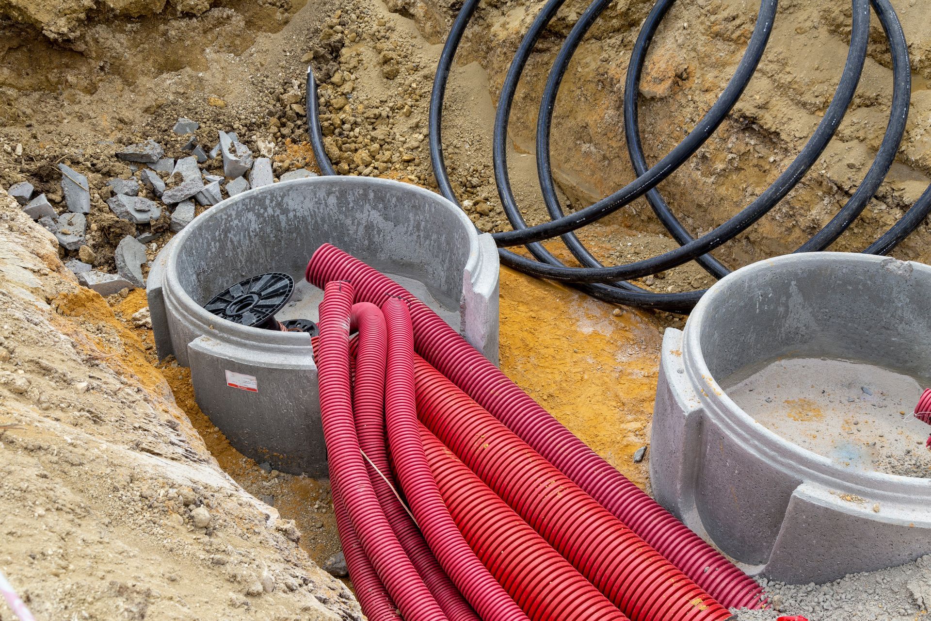 Gros plan sur un regard de visite en béton pour le raccordement et la distribution de gaines rouges électriques