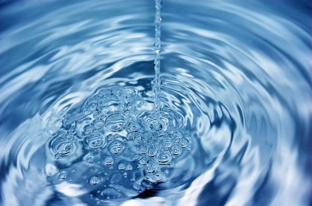 Ondulaciones en el agua azul con un chorro que salpica en el centro