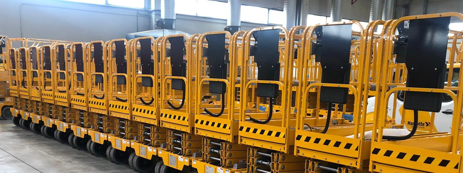 Una fila de vehículos amarillos están alineados en un almacén.