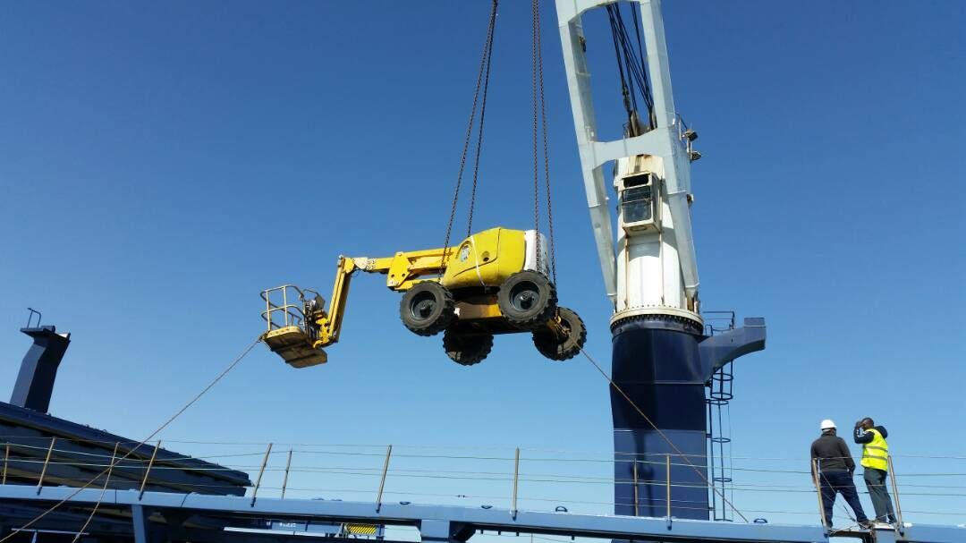 Un vehículo amarillo está siendo levantado por una grúa en un barco.