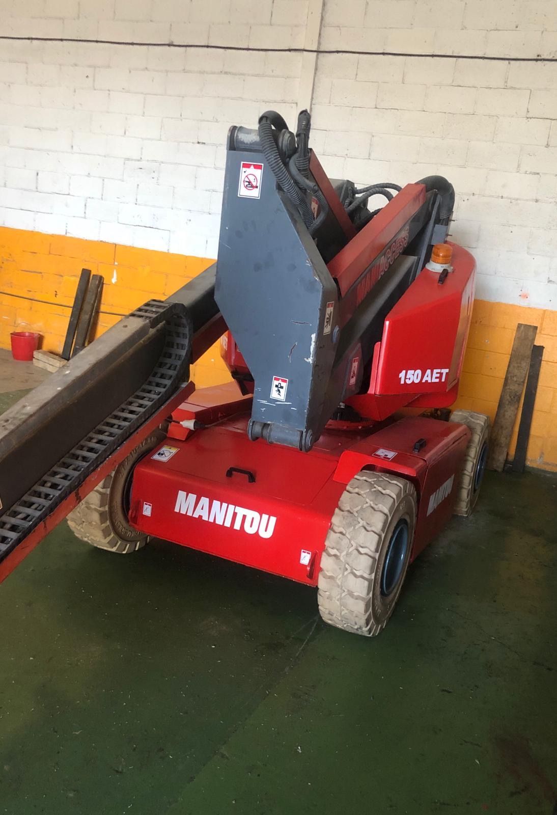 Un elevador Manitou rojo está estacionado en un almacén.