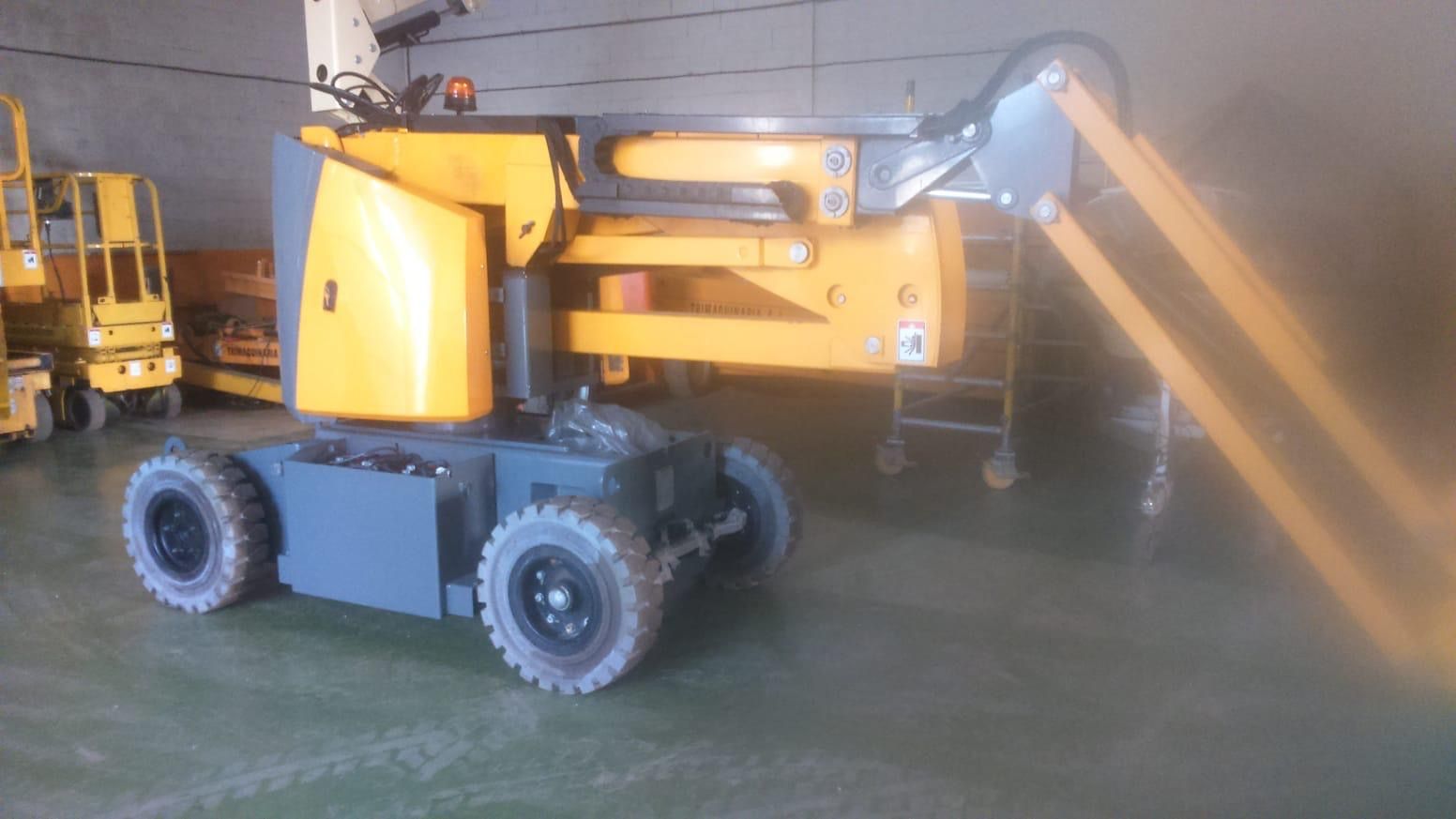 Un elevador aéreo amarillo está estacionado en un almacén.