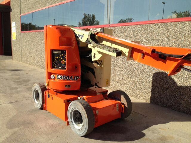 Una excavadora naranja está estacionada frente a un edificio.