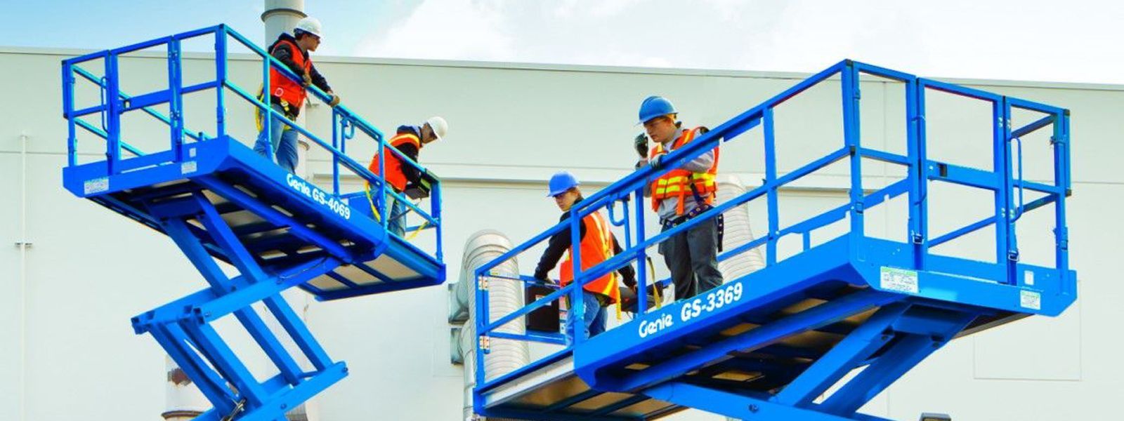 Un grupo de personas está de pie sobre un elevador de tijera azul.