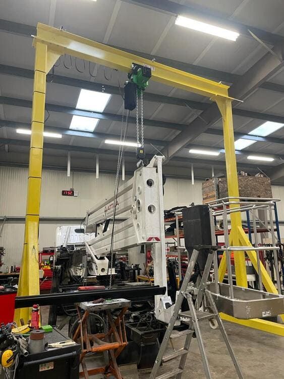 Una grúa amarilla está sentada en un almacén al lado de una escalera.