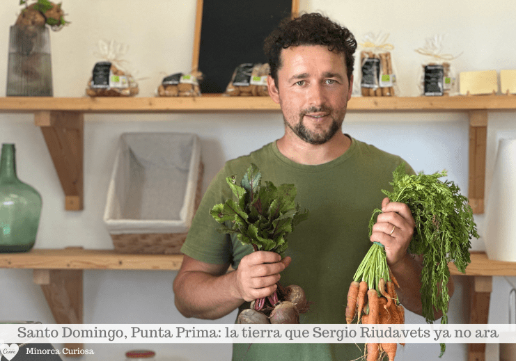 Hombre sosteniendo verduras de hoja verde y hierbas en una cocina con estantes y frascos al fondo.