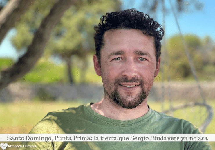 Hombre sonriente al aire libre con camisa verde, con árboles y un paisaje borroso detrás de él.