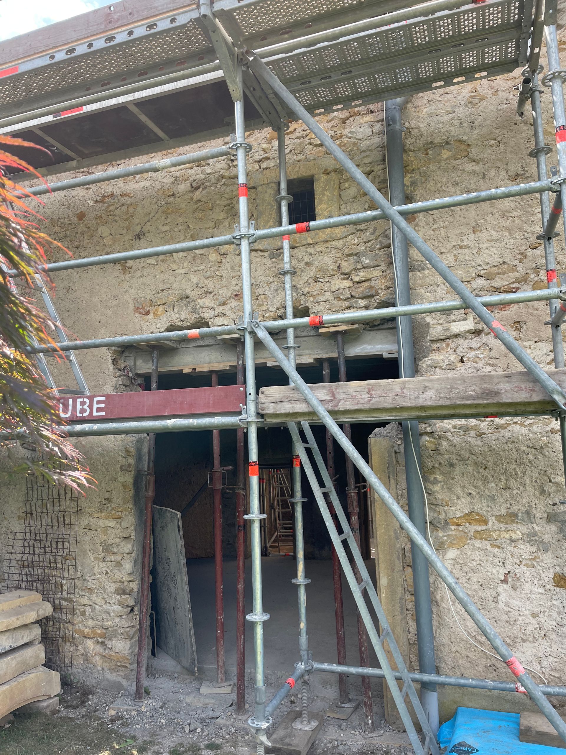 Un échafaudage entoure une ancienne porte en pierre lors d'une rénovation.