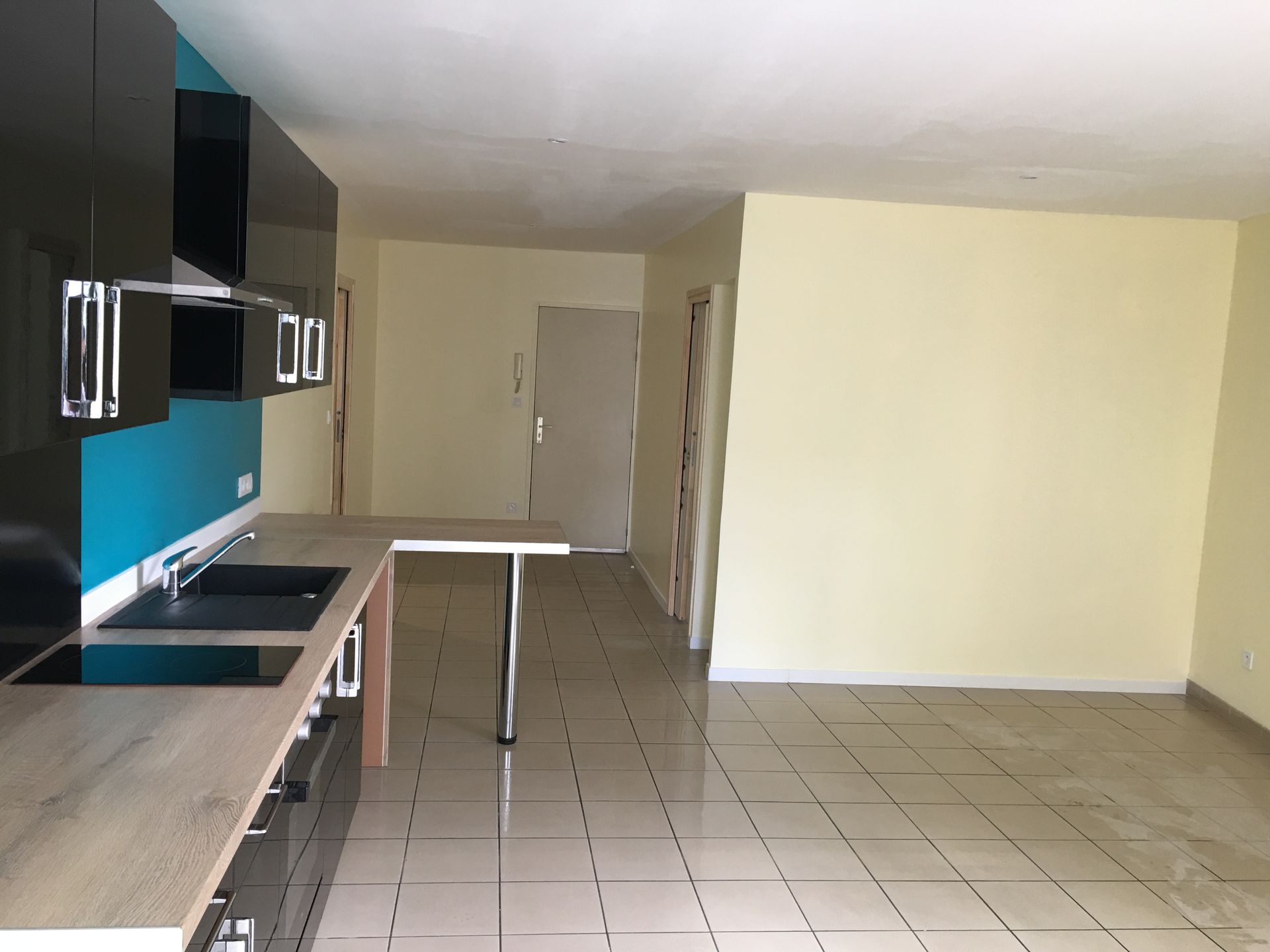 Un homme en tenue de protection pulvérise de la peinture sur le mur d'un bâtiment. Échafaudages et bureaux modernes en arrière-plan.