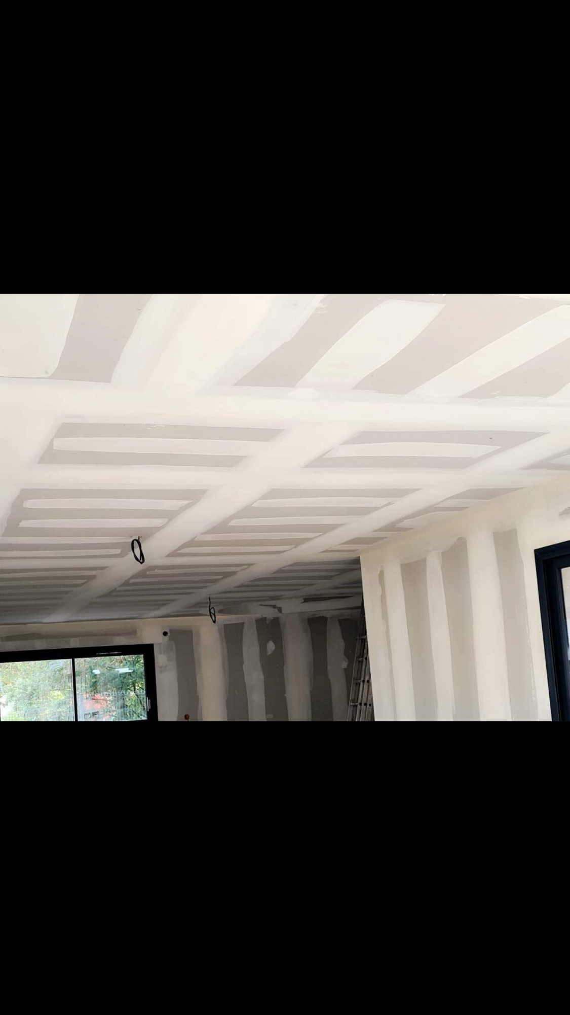 Une femme portant un bonnet rouge tient un appareil photo et prend une photo en extérieur.