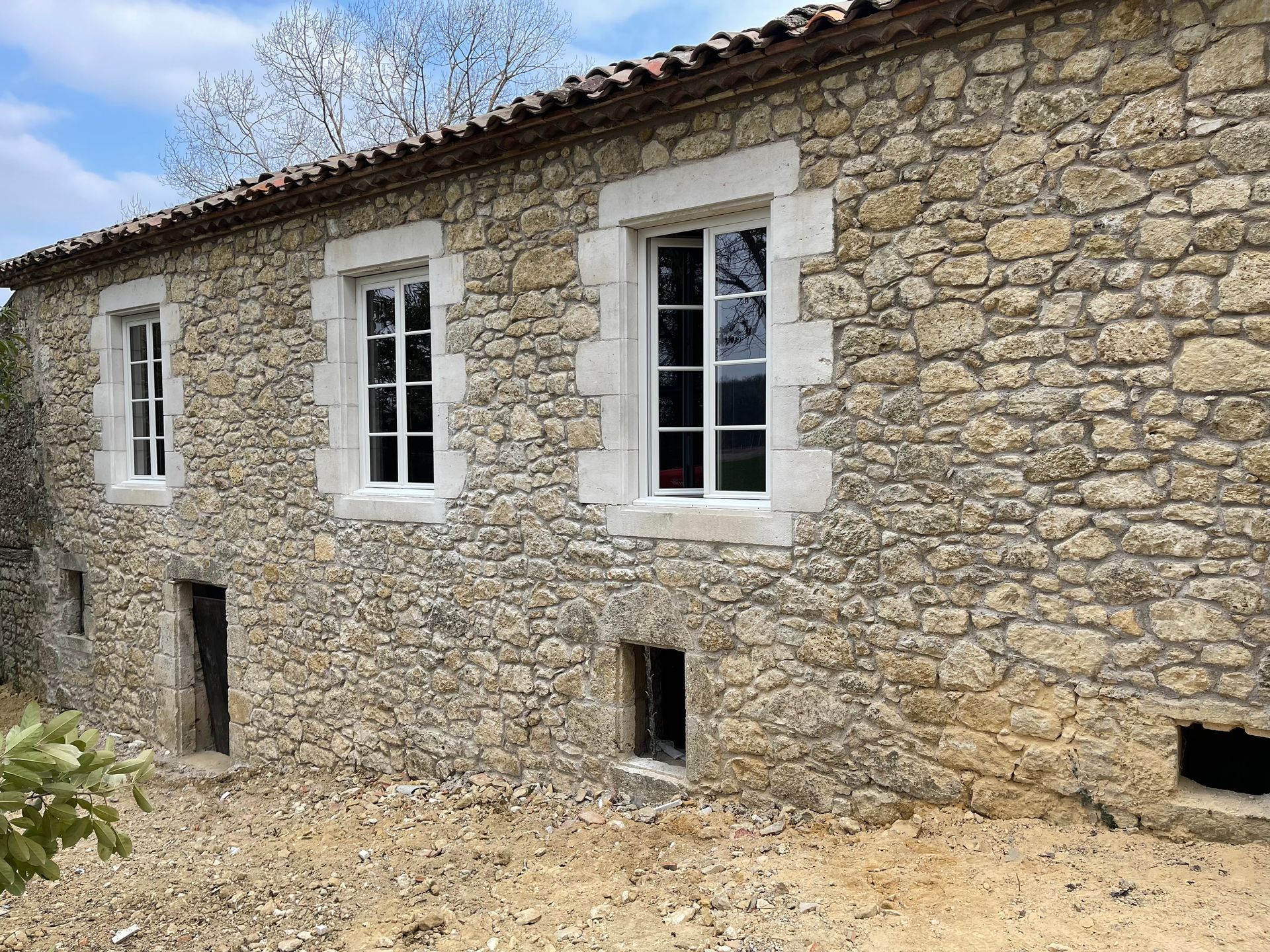 Extension de maison en brique en construction, avec charpente apparente et grandes portes coulissantes.