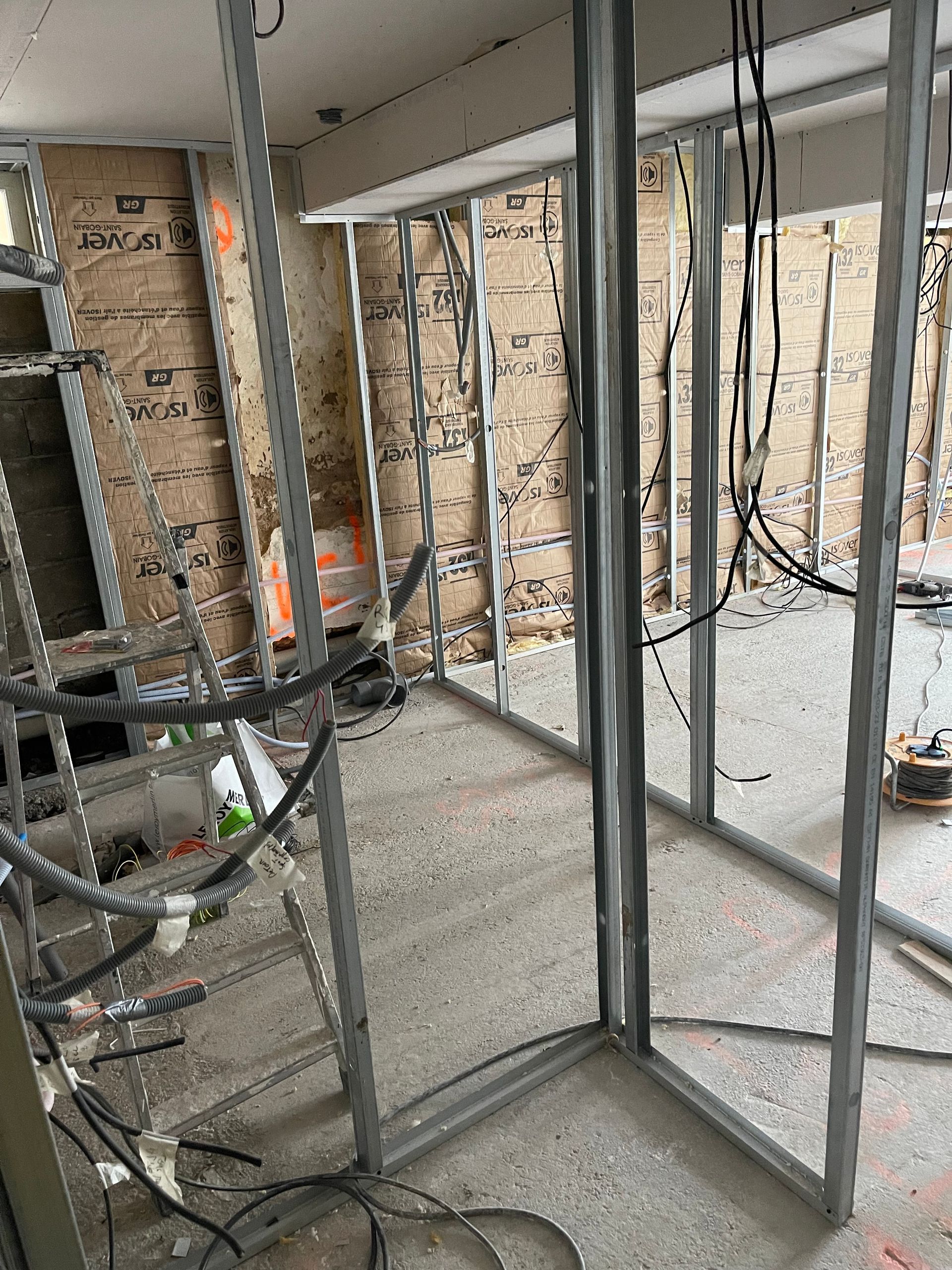 Un électricien travaille sur un tableau électrique, utilisant un tournevis pour connecter des fils.