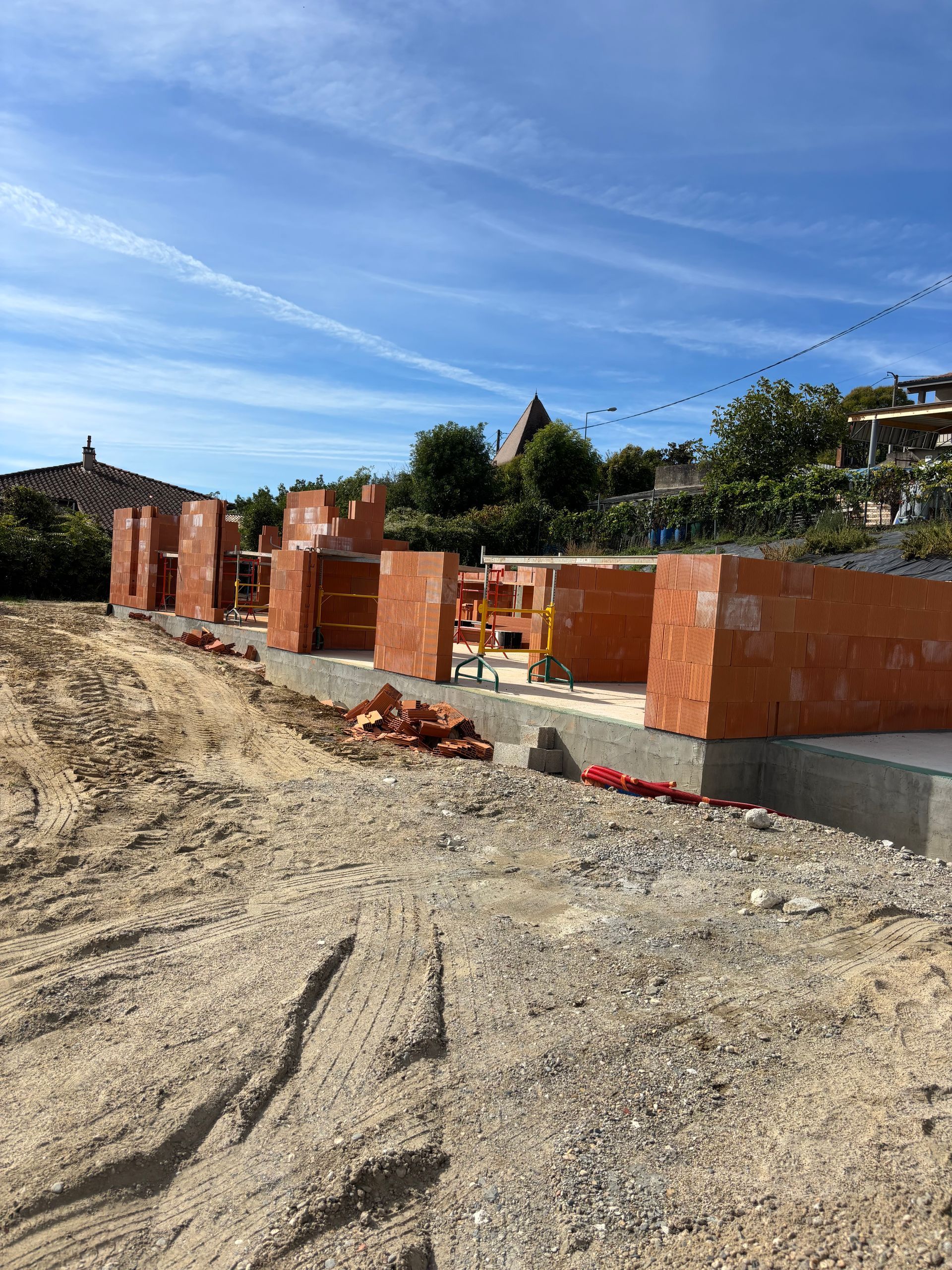 Une femme portant un bonnet rouge tient un appareil photo et prend une photo en extérieur.
