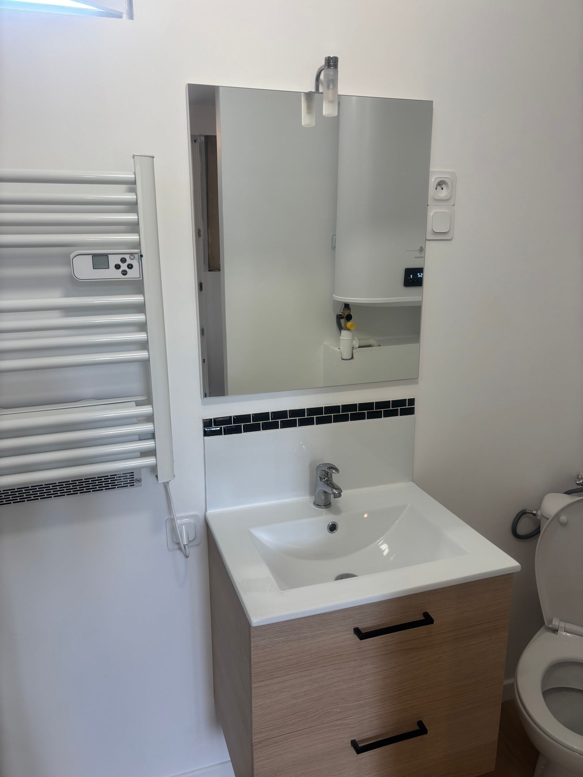 Salle de bains avec baignoire blanche, mur carrelé vert et porte en bois rustique.