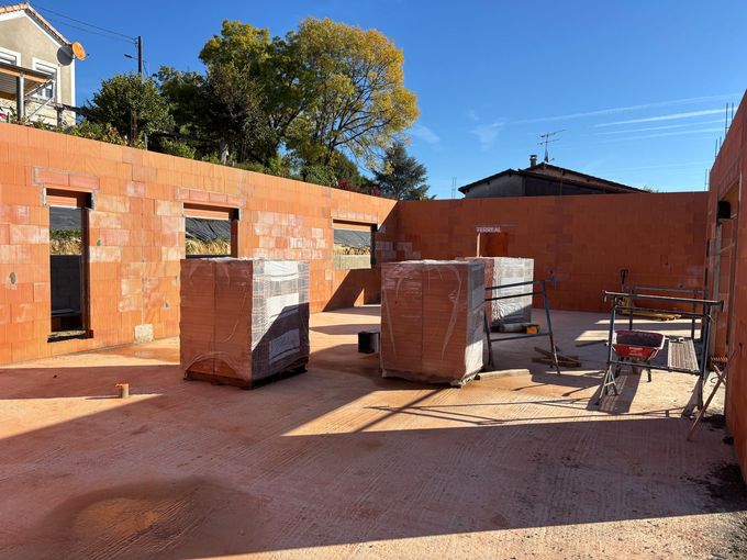 Bâtiment en pierre avec des encadrements de fenêtres blancs et un toit de tuile rouge.