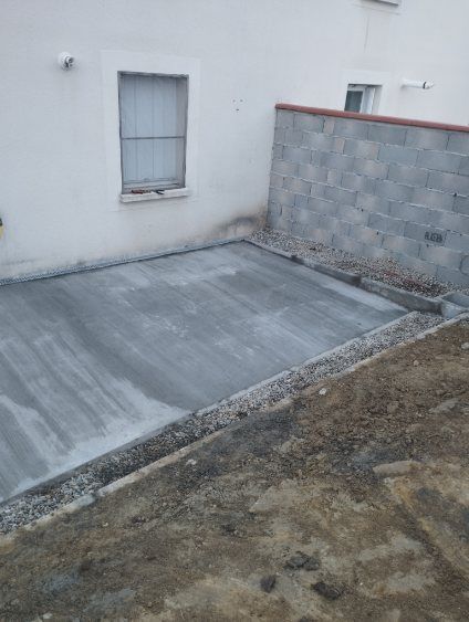 Extension de maison en brique en construction, avec charpente apparente et grandes portes coulissantes.