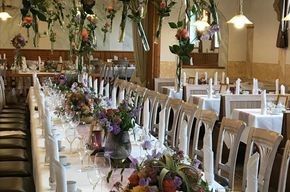 Ein langer Tisch in einem Restaurant, dekoriert mit Blumen und Kerzen.