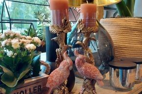Ein paar Flamingos sitzen mit Kerzen auf einem Tisch.