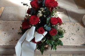 Ein Strauß roter Rosen mit einer weißen Schleife auf einer Steintreppe.