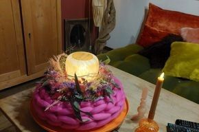 Auf einem Tisch steht ein rosa Kuchen mit einer Kerze darauf.