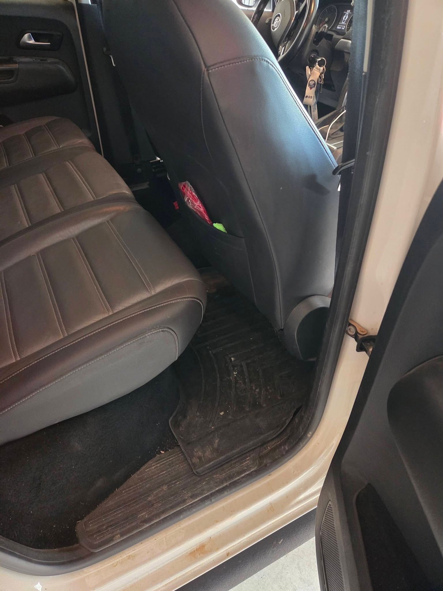Intérieur de la voiture avec sièges en cuir noir et tapis de sol mouillé et boueux près de la porte arrière ouverte
