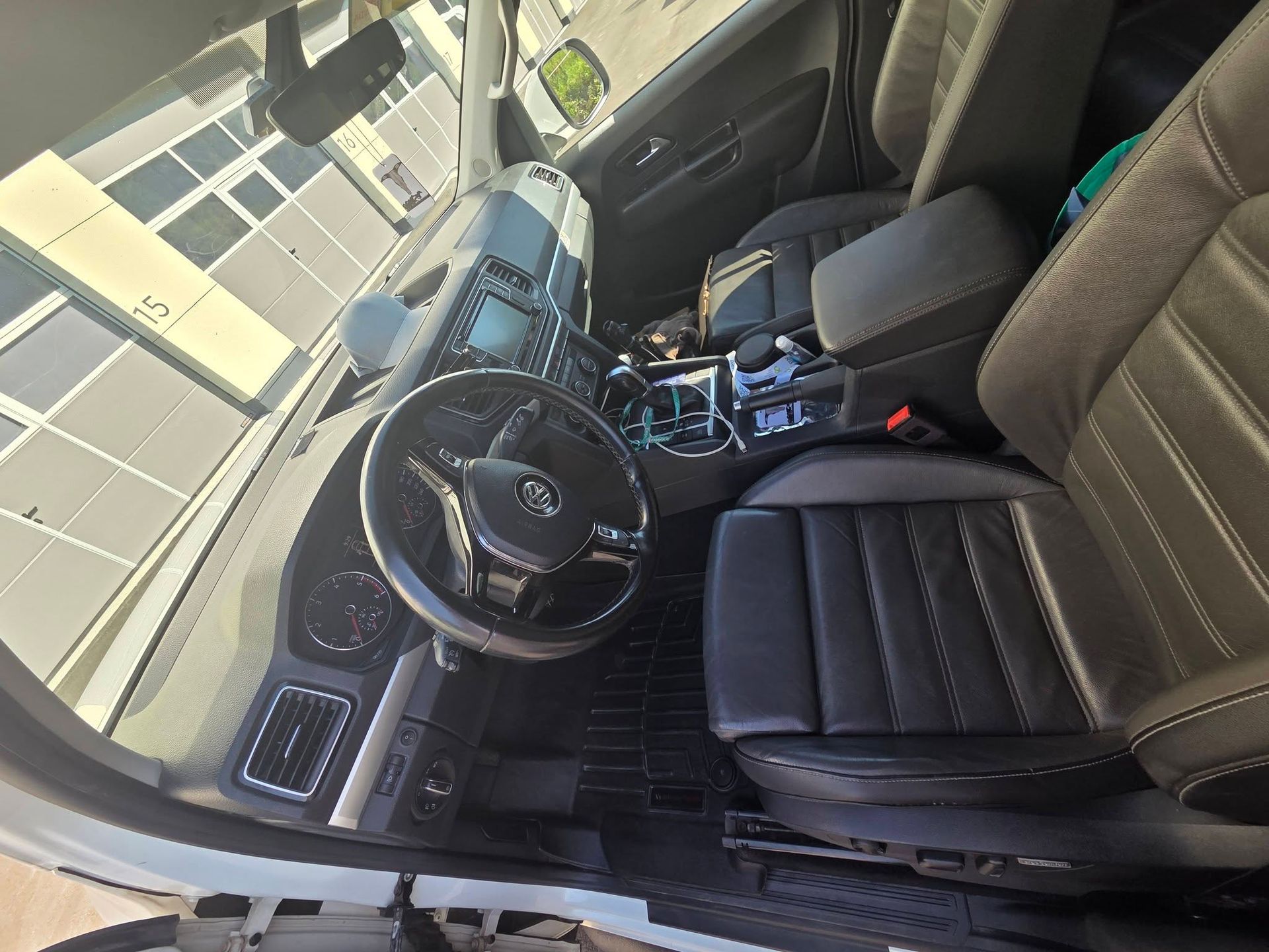 Intérieur de la voiture avec sièges, volant et console centrale en cuir noir, vu du côté conducteur.