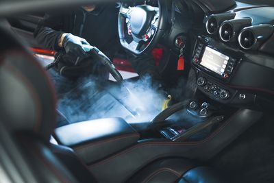Intérieur de voiture de sport en fibre de carbone avec tableau de bord éclairé, fumée blanche et conducteur ganté au volant
