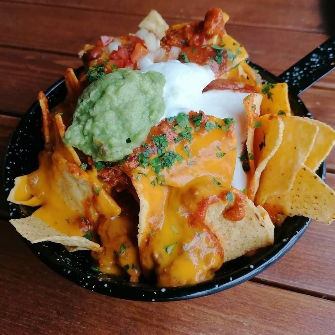Nachos con queso naranja derretido, guacamole, crema agria y salsa 