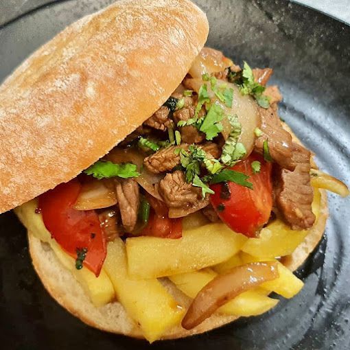 Un primer plano de un sándwich con papas fritas y carne en un plato.